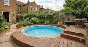 Small round swimming pool surrounded by timber decking in a typical UK back garden.