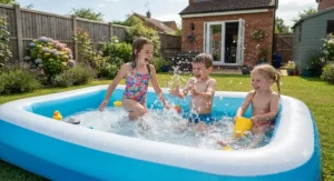 Children splashing and playing happily together in a spacious family paddling pool on a sunny day.