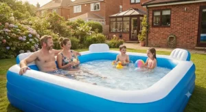 Parents relaxing on built-in seats inside a large family paddling pool while watching children play in the garden