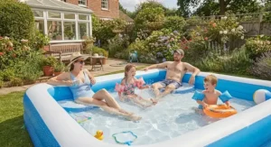 Family enjoying and paddling in a blue rectangular inflatable pool during the school summer holidays